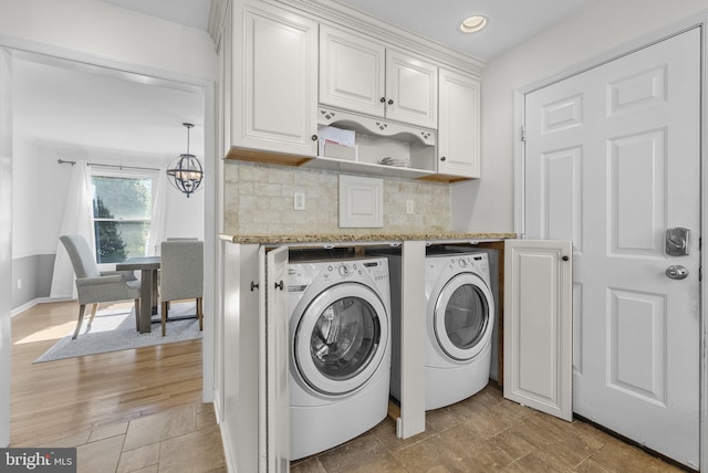 laundry room with laundry area, independent washer and dryer, light wood finished floors, and a chandelier