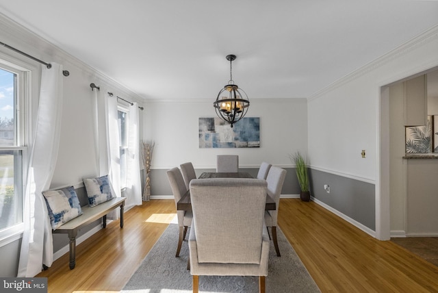 dining room with baseboards, a notable chandelier, light wood-style flooring, and crown molding