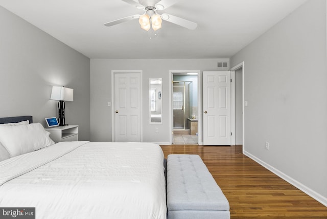 bedroom featuring visible vents, ensuite bathroom, wood finished floors, baseboards, and ceiling fan