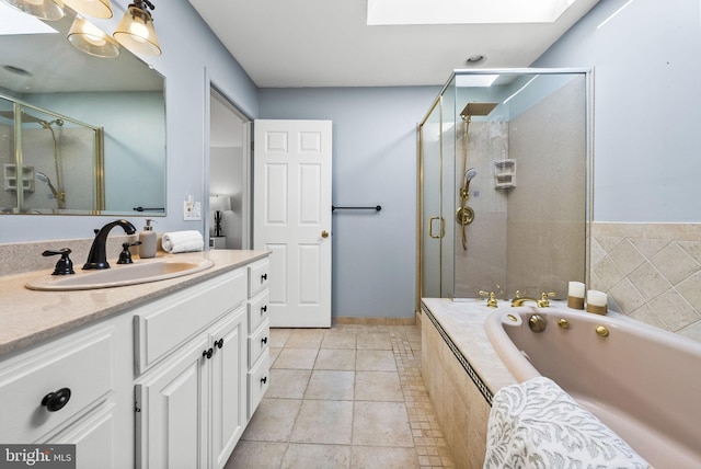 bathroom with vanity, a skylight, a shower stall, a garden tub, and tile patterned floors