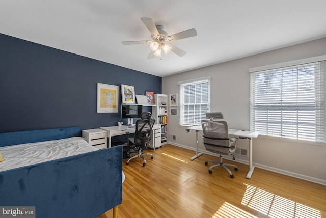 home office featuring a wealth of natural light, ceiling fan, baseboards, and wood finished floors