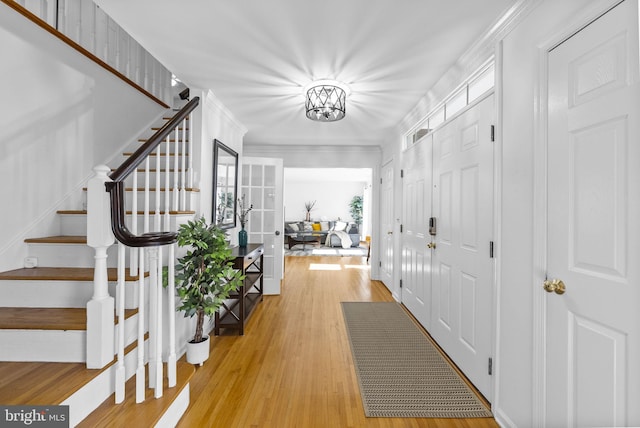 foyer entrance with stairway, light wood-type flooring, and ornamental molding