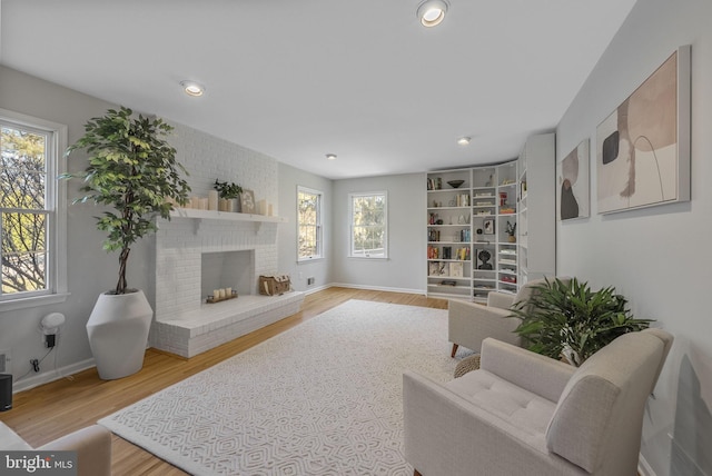 living room featuring recessed lighting, a fireplace, baseboards, and wood finished floors