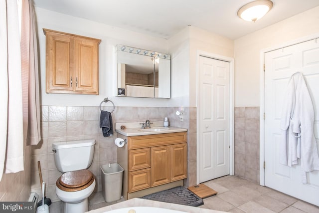 full bathroom featuring vanity, wainscoting, tile walls, toilet, and tile patterned floors