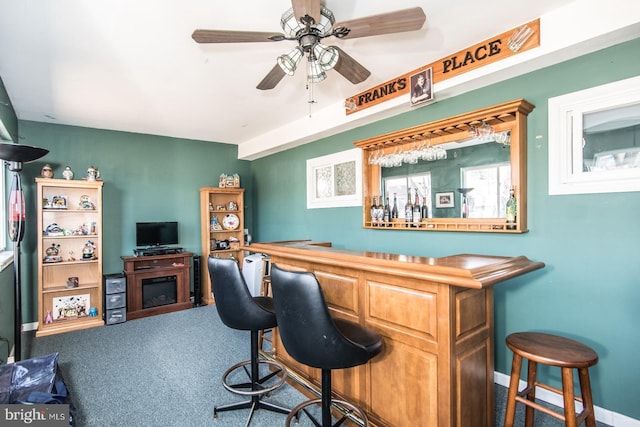 bar with baseboards, a bar, a ceiling fan, and carpet floors