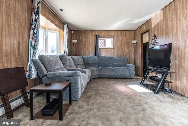 carpeted living room featuring visible vents, wood walls, and a baseboard radiator