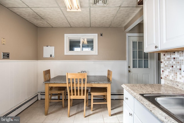 dining area with a baseboard radiator, a wainscoted wall, and light tile patterned flooring