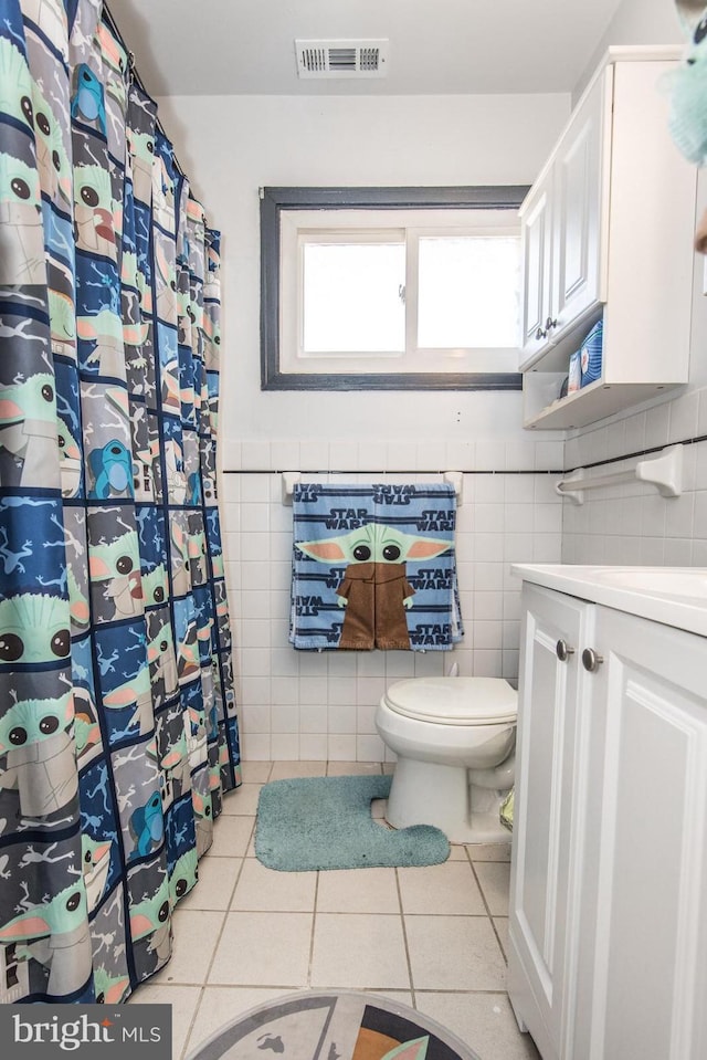 bathroom with a shower with curtain, visible vents, tile patterned flooring, tile walls, and toilet