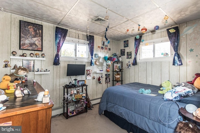 carpeted bedroom featuring visible vents, multiple windows, wooden walls, and a baseboard radiator