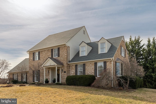 view of front of house featuring a front yard, brick siding, and a shingled roof