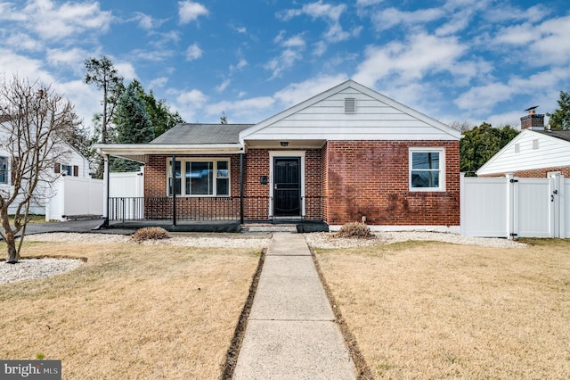 bungalow-style house with brick siding, fence, a front yard, covered porch, and a gate