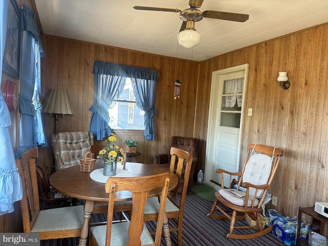 dining room featuring wood walls and a ceiling fan