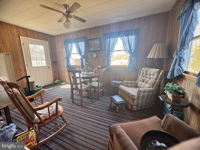 interior space featuring ceiling fan and wood walls