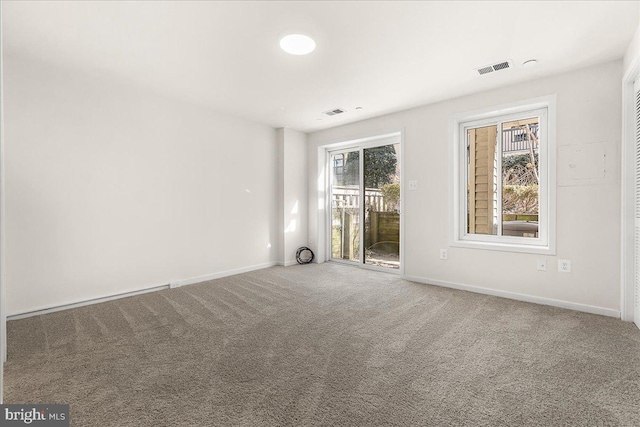 spare room featuring carpet flooring, visible vents, and baseboards