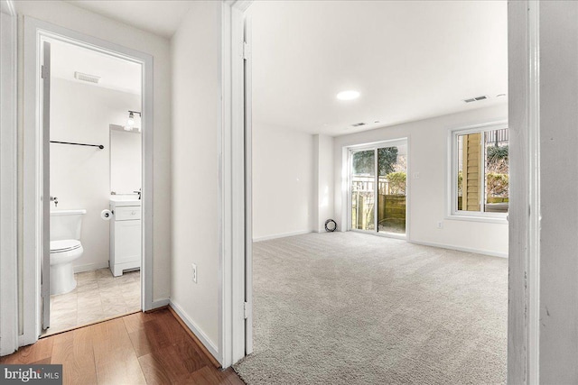 hallway featuring visible vents, baseboards, and carpet