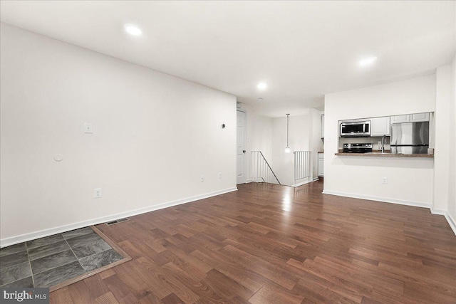 unfurnished living room featuring dark wood finished floors, visible vents, recessed lighting, and baseboards