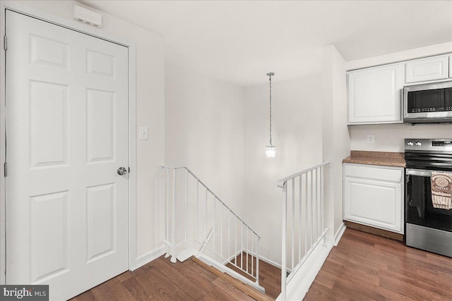 kitchen featuring dark wood-style floors, white cabinets, appliances with stainless steel finishes, and baseboards