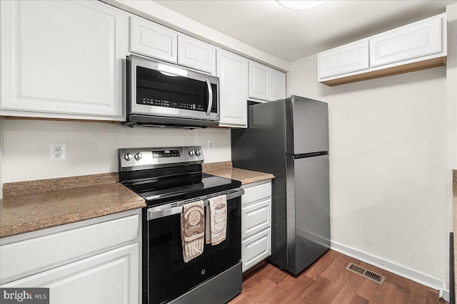 kitchen featuring white cabinets, appliances with stainless steel finishes, and dark wood-type flooring