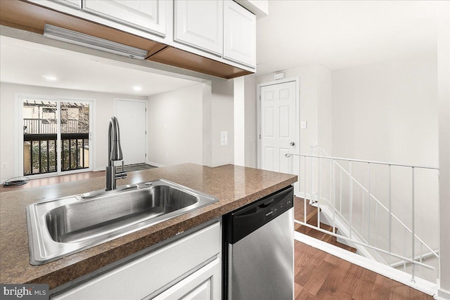 kitchen featuring a sink, dark countertops, wood finished floors, white cabinetry, and dishwasher