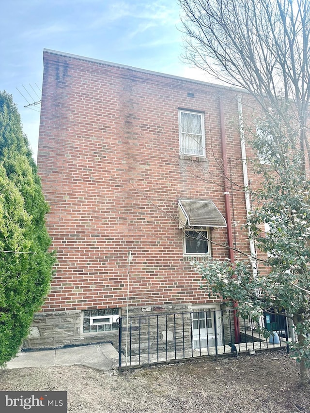 view of property exterior with brick siding and fence