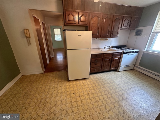 kitchen featuring a sink, white appliances, light countertops, baseboards, and light floors