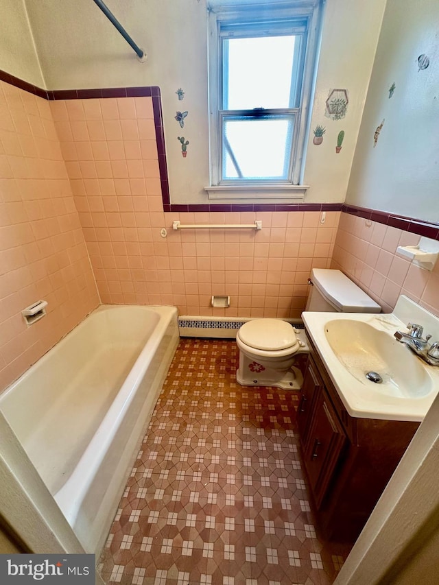 bathroom with baseboard heating, tile walls, vanity, and toilet