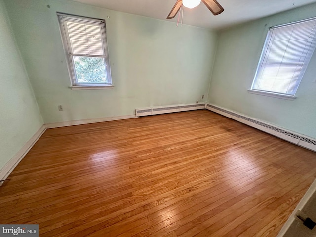 spare room featuring baseboards, hardwood / wood-style flooring, a ceiling fan, and a baseboard radiator