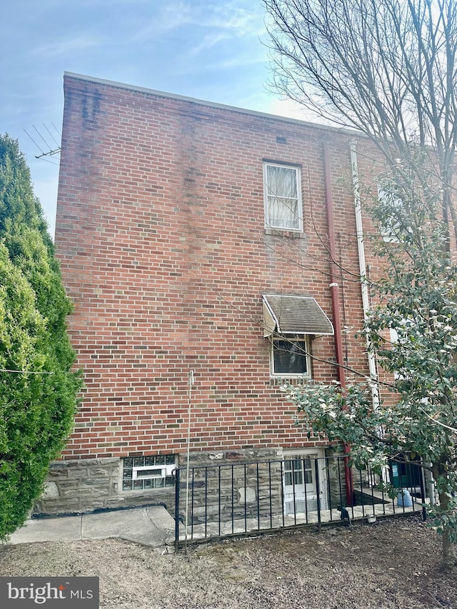 view of side of home featuring brick siding and fence