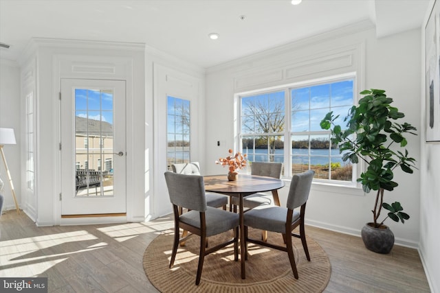 dining space with a wealth of natural light, visible vents, light wood-style floors, and ornamental molding