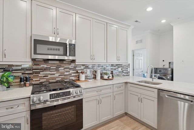 kitchen featuring visible vents, a sink, backsplash, appliances with stainless steel finishes, and crown molding