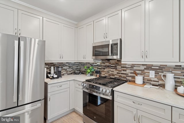 kitchen featuring light wood-style floors, light stone countertops, backsplash, and appliances with stainless steel finishes