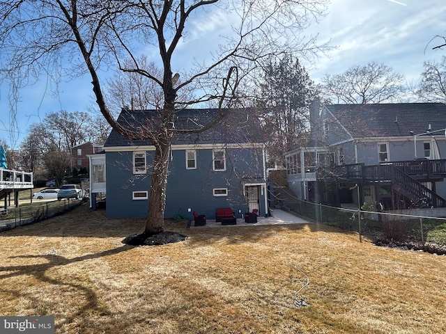 back of house featuring a wooden deck, a lawn, stairs, and fence