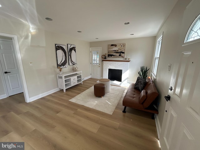 living area featuring a wealth of natural light, a brick fireplace, and wood finished floors