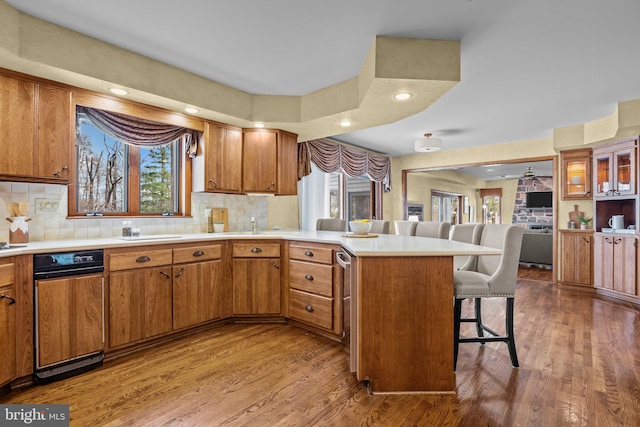 kitchen with a kitchen breakfast bar, a peninsula, wood finished floors, and brown cabinetry