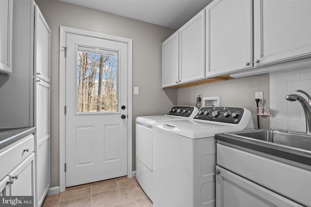 laundry area with a sink, cabinet space, washing machine and dryer, and light tile patterned flooring