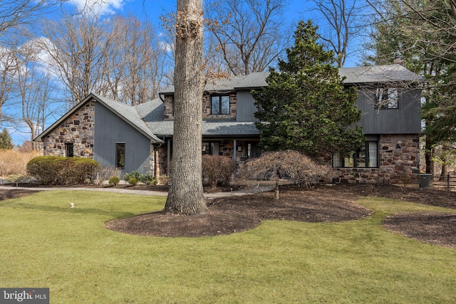 view of front facade with a front lawn, stone siding, and a shingled roof