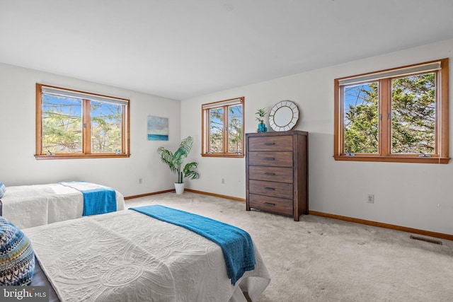 bedroom with visible vents, light carpet, and baseboards