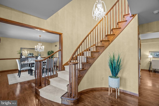 stairs featuring baseboards, a notable chandelier, and wood finished floors