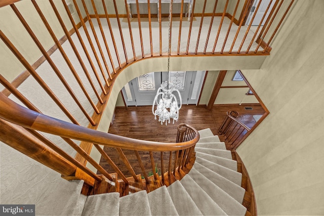 stairway featuring arched walkways, a notable chandelier, and a high ceiling