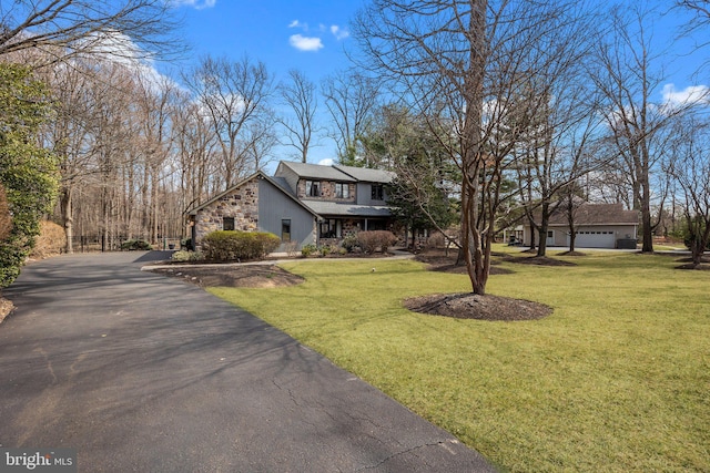 view of front of house featuring stone siding, a garage, driveway, and a front yard