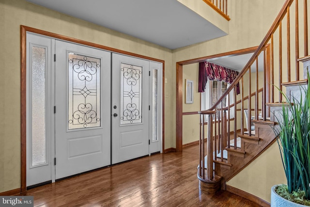 entryway with baseboards, wood finished floors, and stairs