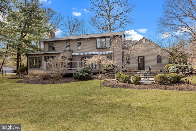 rear view of property with a lawn, a chimney, a patio, and a sunroom