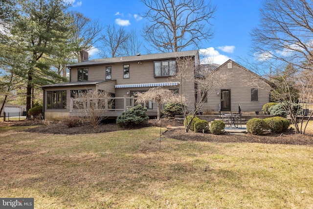 back of house featuring a lawn, a chimney, a patio, and a sunroom