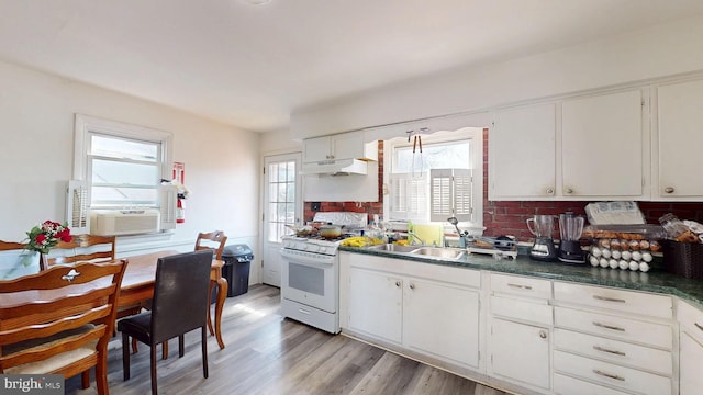 kitchen featuring gas range gas stove, a sink, white cabinetry, dark countertops, and light wood-type flooring