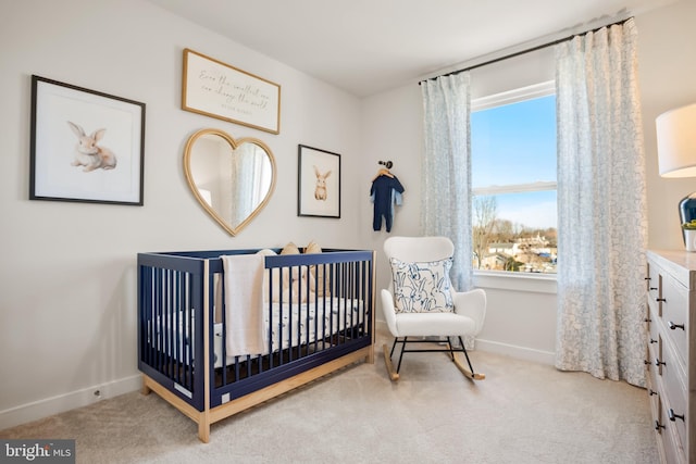 carpeted bedroom with a crib and baseboards