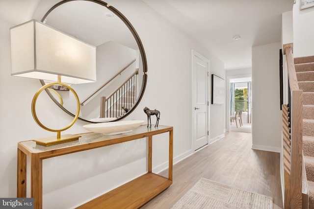 hallway featuring stairway, baseboards, and wood finished floors