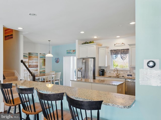 kitchen featuring a breakfast bar area, a kitchen island, appliances with stainless steel finishes, and a sink