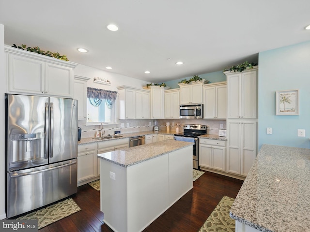 kitchen with a kitchen island, dark wood finished floors, decorative backsplash, stainless steel appliances, and a sink