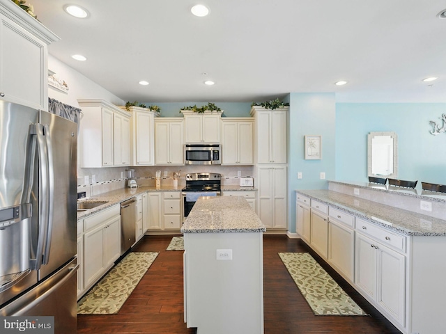 kitchen featuring a center island, dark wood-style flooring, backsplash, and stainless steel appliances