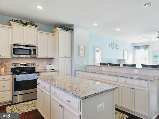 kitchen featuring a ceiling fan, a kitchen island, recessed lighting, appliances with stainless steel finishes, and dark wood-style flooring